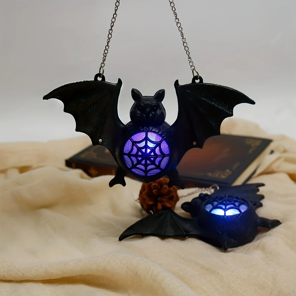 Lámpara de murciélago LED suspendida sobre una mesa decorativa con iluminación ambiental de Halloween.