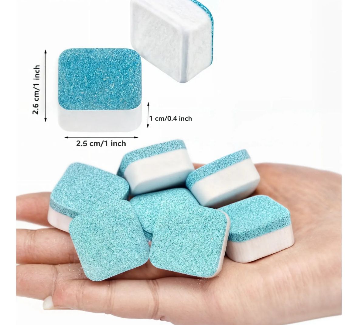 Mano sosteniendo varias pastillas limpiadoras de lavadora mostrando sus dimensiones físicas de 2.6 cm por 2.5 cm y 1 cm de grosor.