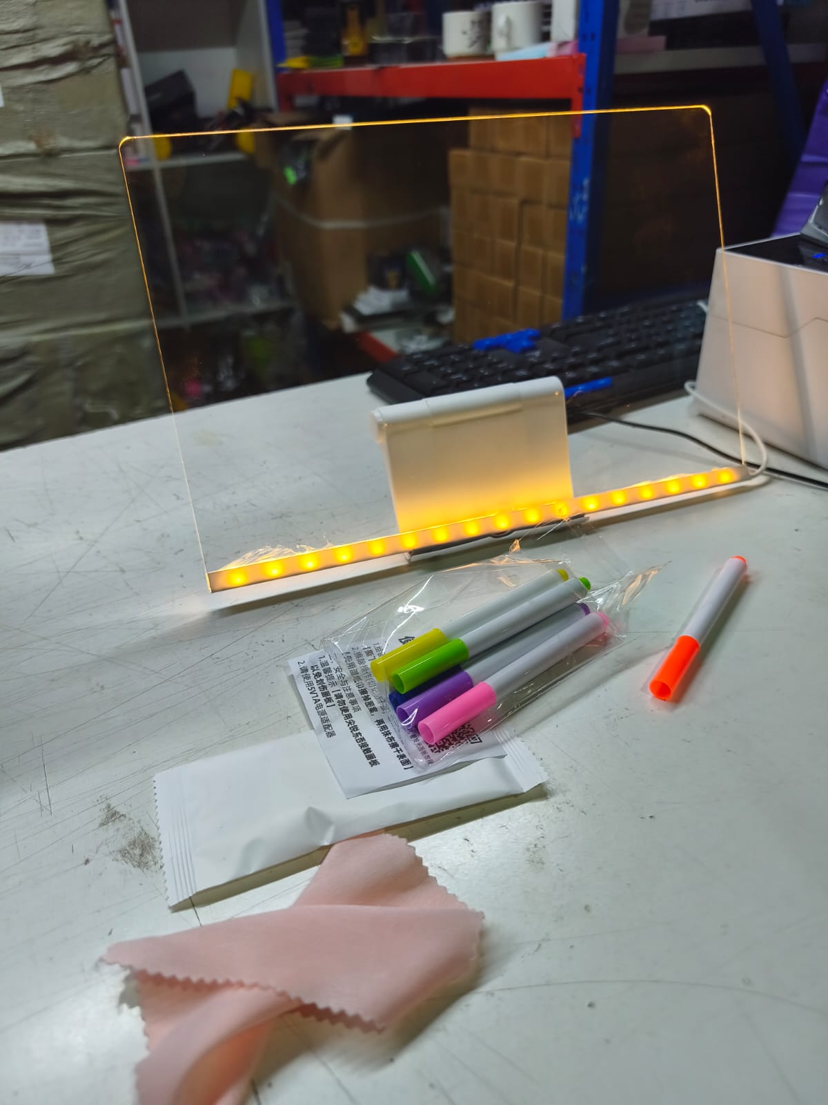 Vista real de la pizarra LED acrílica iluminada sobre un escritorio con sus accesorios en Chile