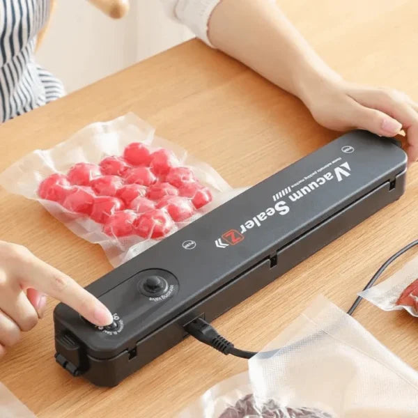 Persona operando selladora al vacío automática CurlerPro sobre mesa de madera para conservar frutas en bolsas gofradas